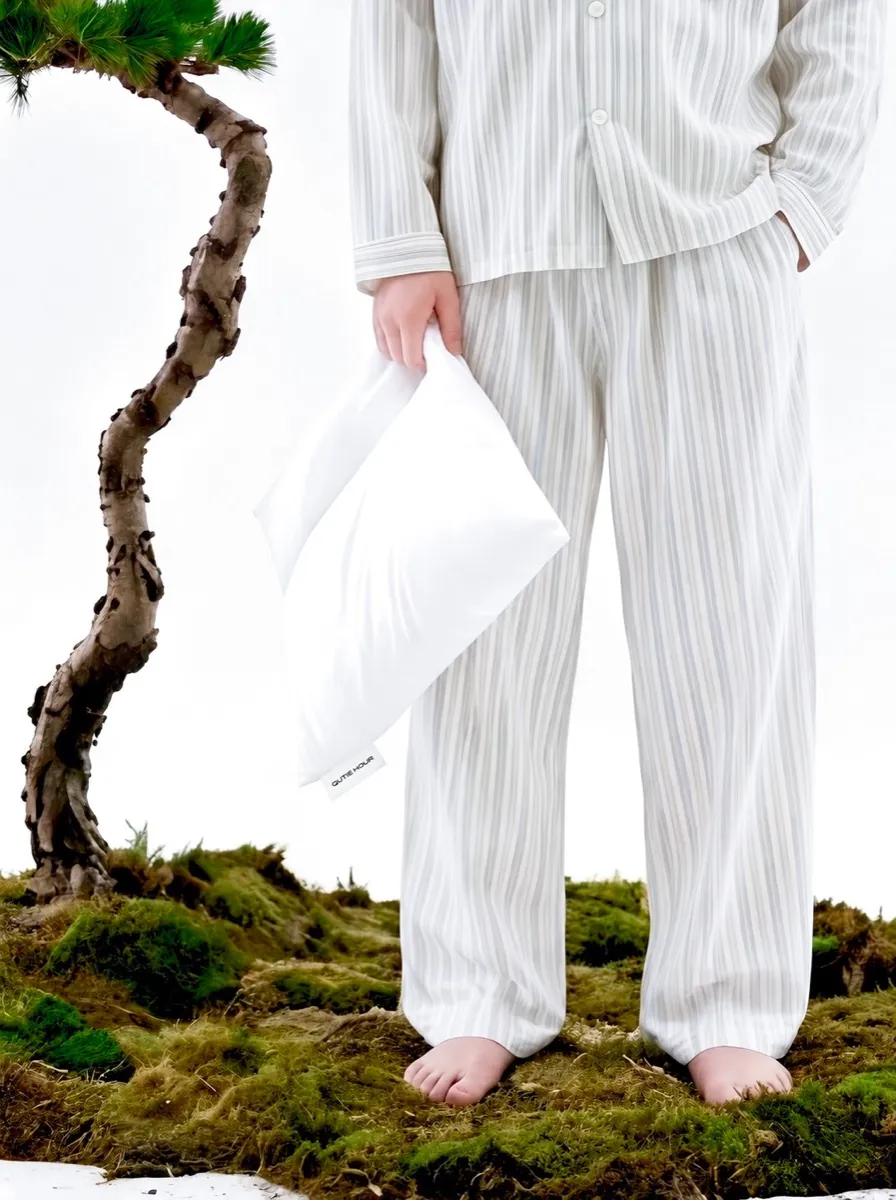 QUIET HOUR — white-clothed figure beside moss and a sculptural tree form, serene natural atmosphere
