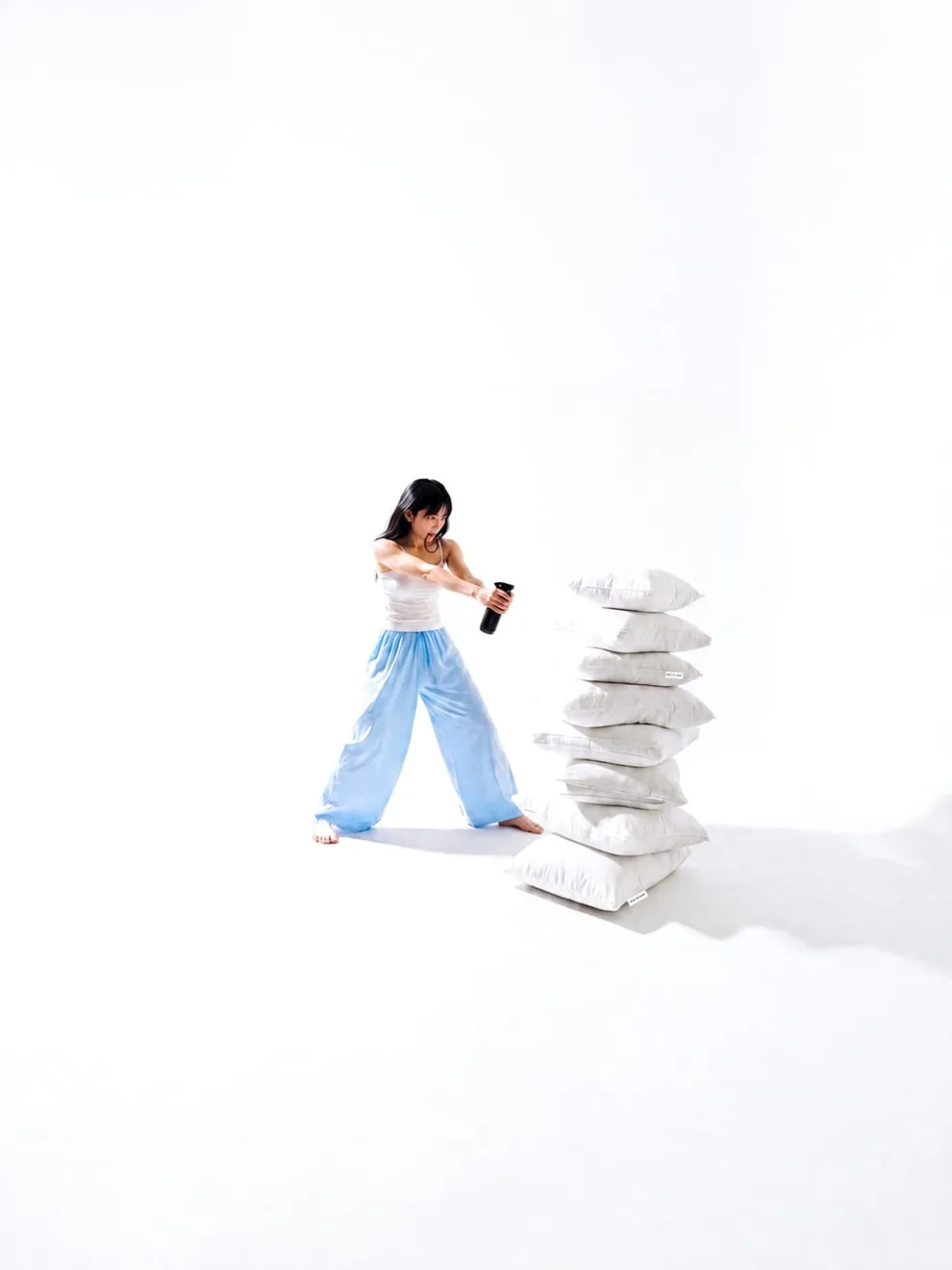 QUIET HOUR — figure pointing a spray bottle toward a stack of white pillows, quiet spacious mood